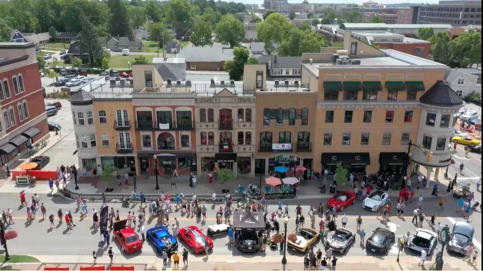 aerial street view with line of cars and crowd